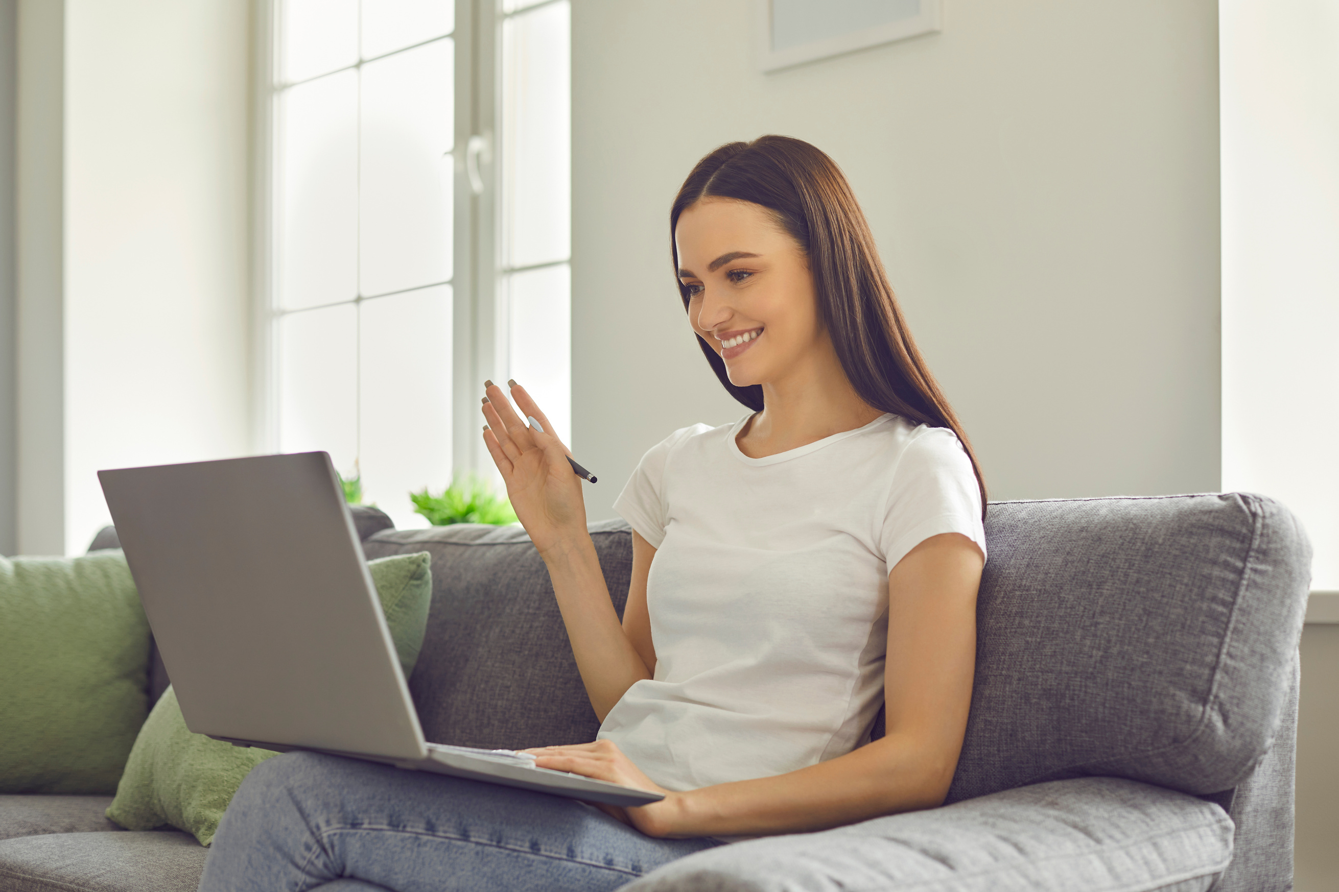 Smiling Young Teacher Waving Hand at Laptop Screen Greeting Her Student and Beginning Online Lesson